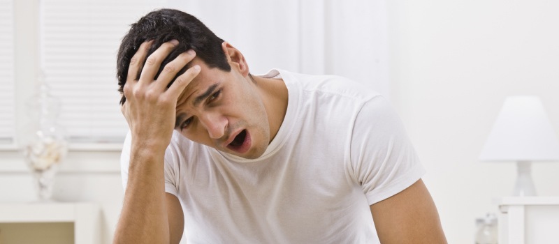 Closeup of a brunette man with obstructive sleep apnea yawning because he suffers from daytime drowsiness