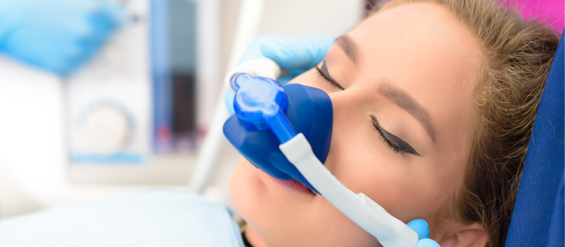 Closeup of a woman wearing a nitrous oxide nose mask for a post about the history of dental sedation