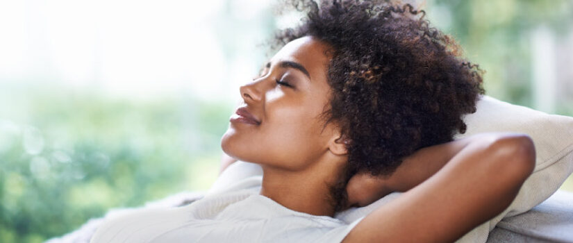 Young woman with dark curly hair relaxes in the backyard.