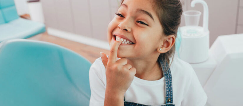 young girl points to her loose front tooth